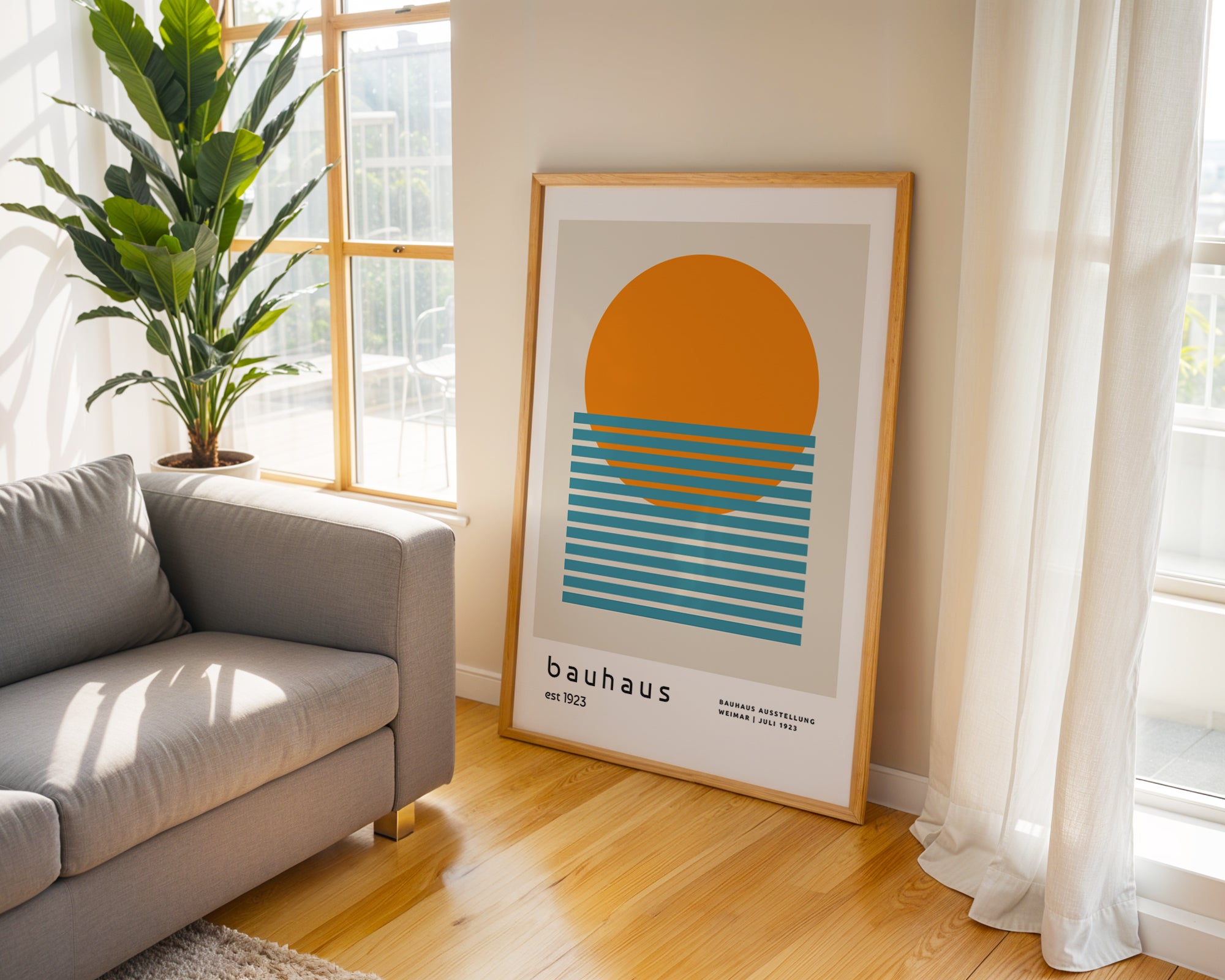 Framed Bauhaus poster on a wall in a bright living room with a sofa and plant.