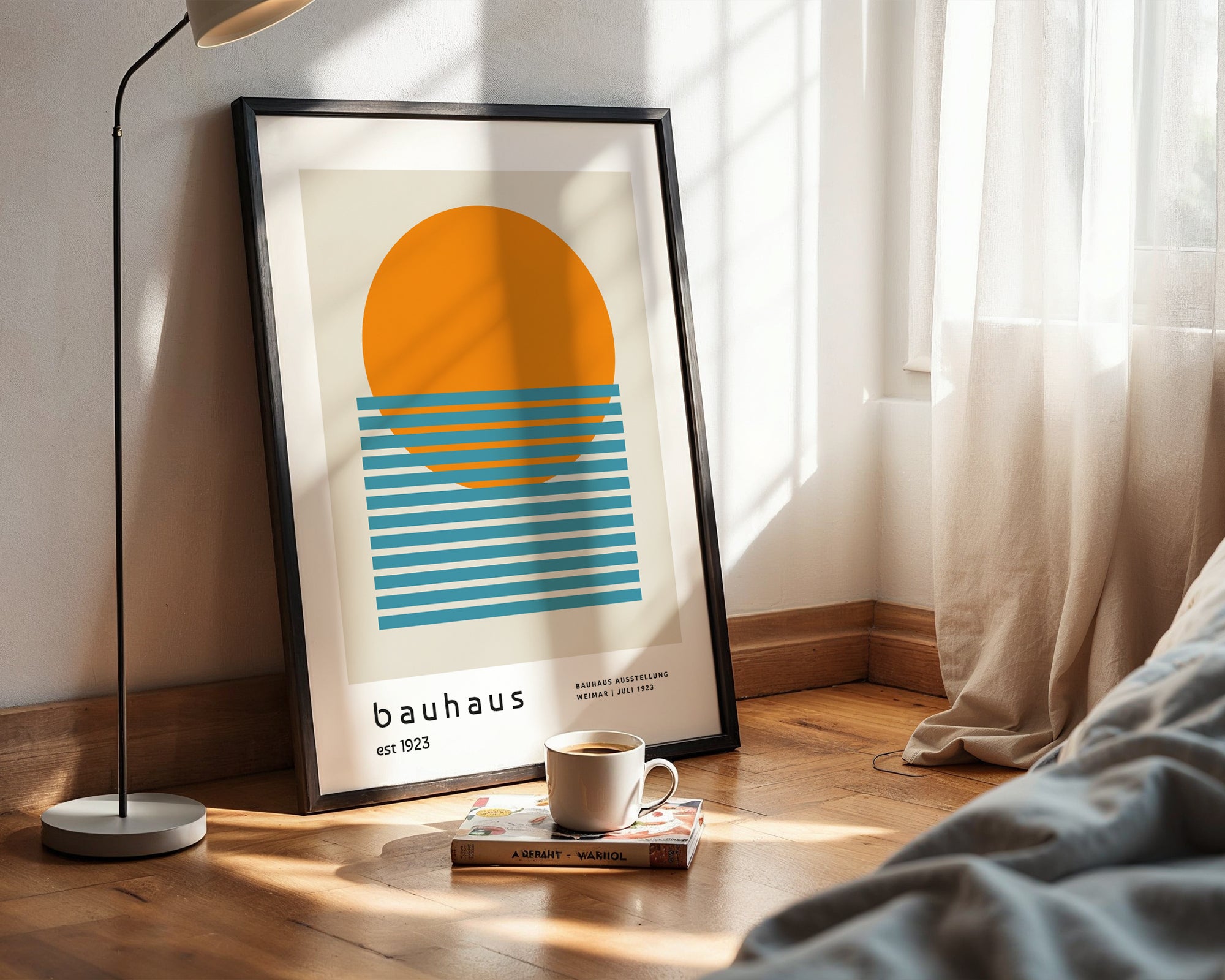 Framed abstract art print on a wall with a cup and book on a surface below.