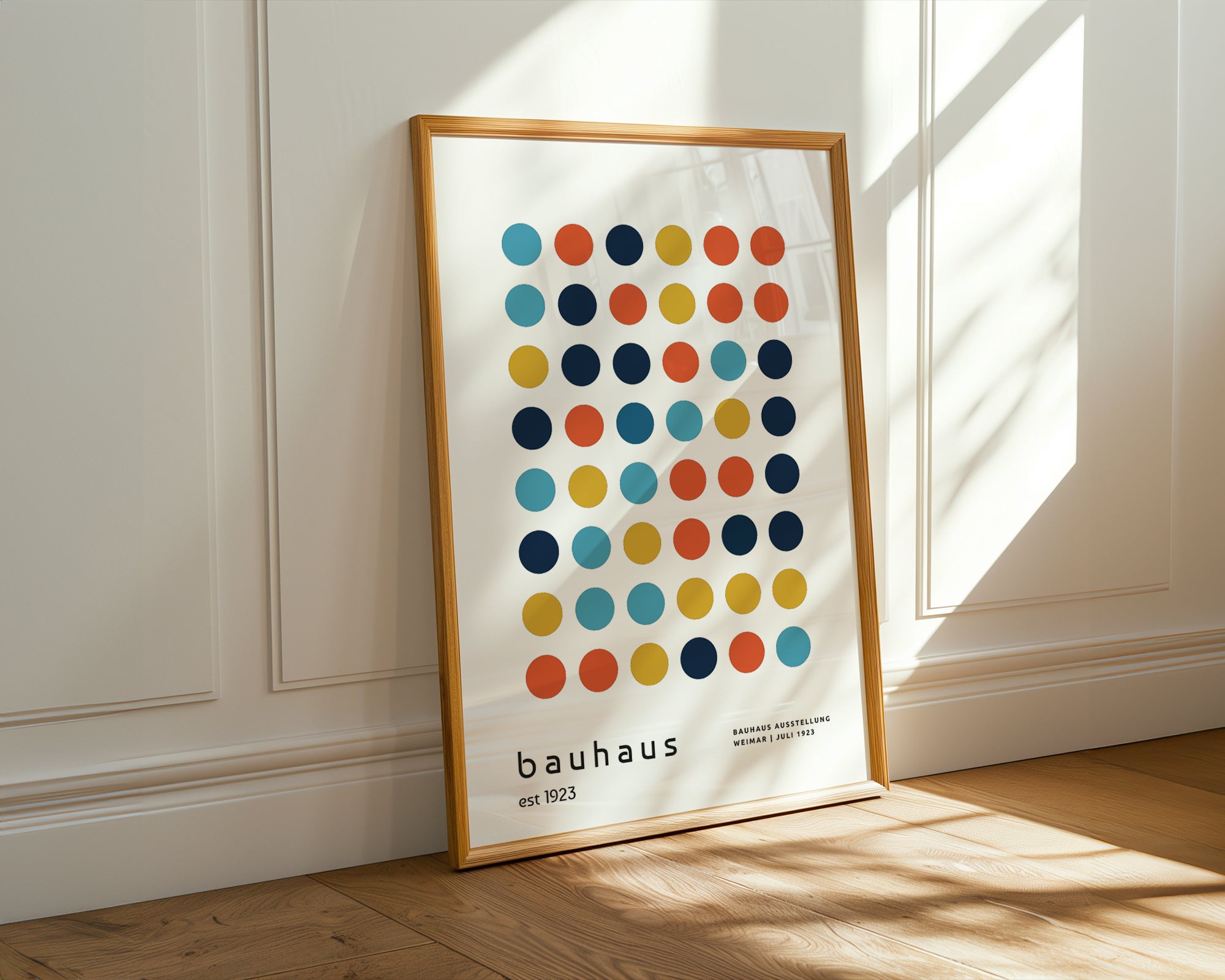 Framed Bauhaus poster with colorful circles on a white background, leaning against a wall.