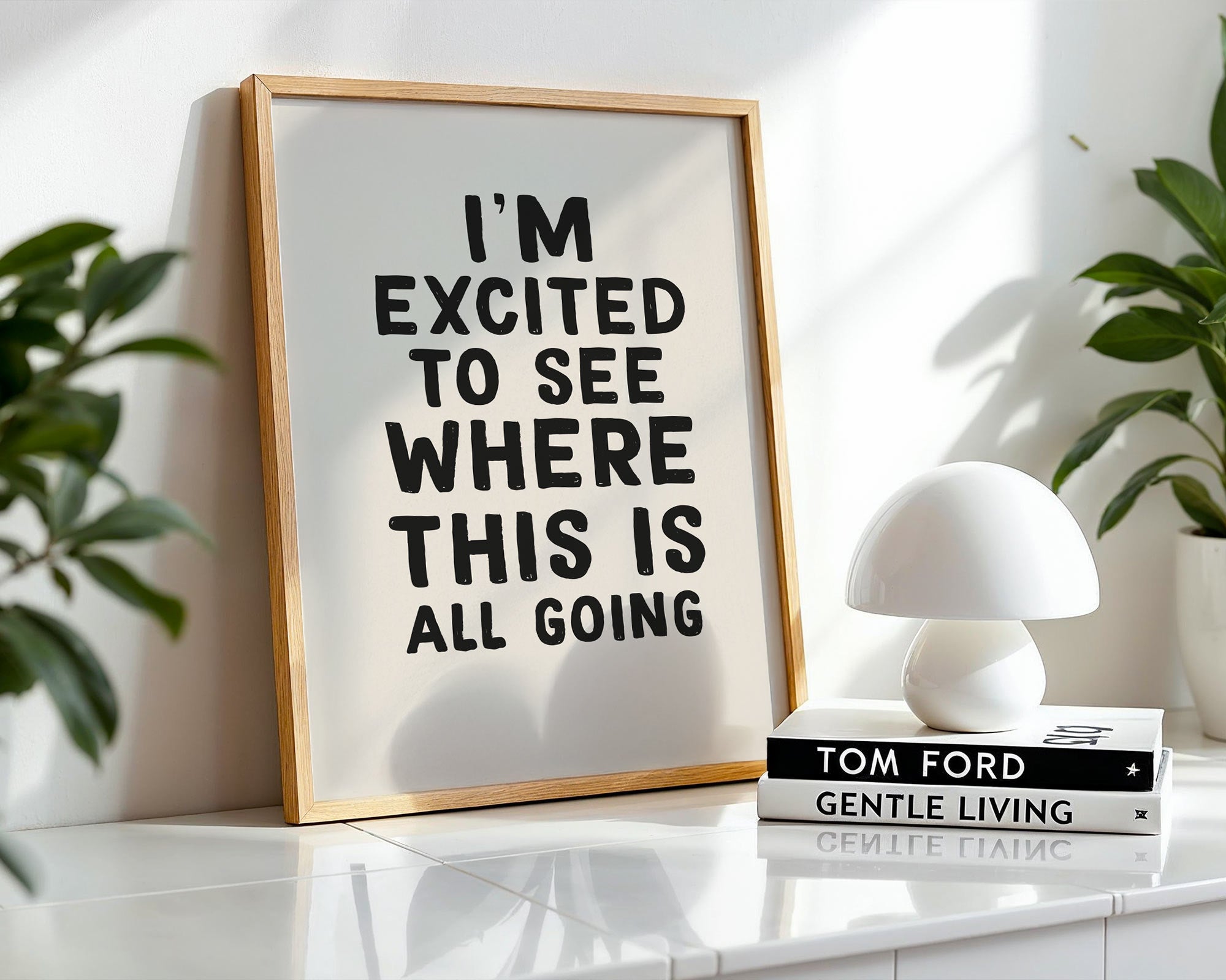 Framed print with motivational quote on a shelf with books and plants