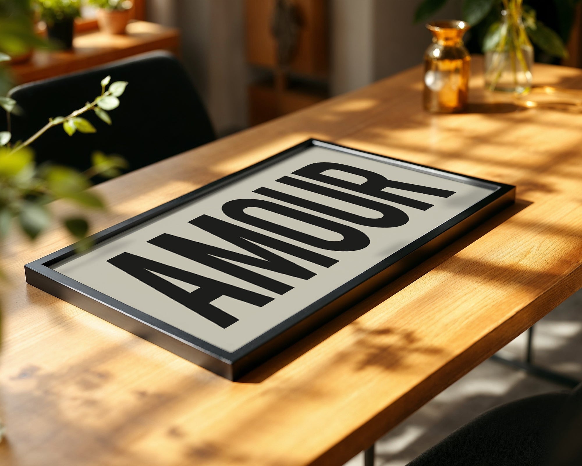 Decorative sign with the word 'AMOUR' on a wooden table with plants and decor in the background.