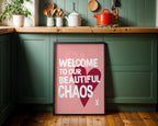 Framed poster with 'Welcome to our beautiful chaos' text in a kitchen setting