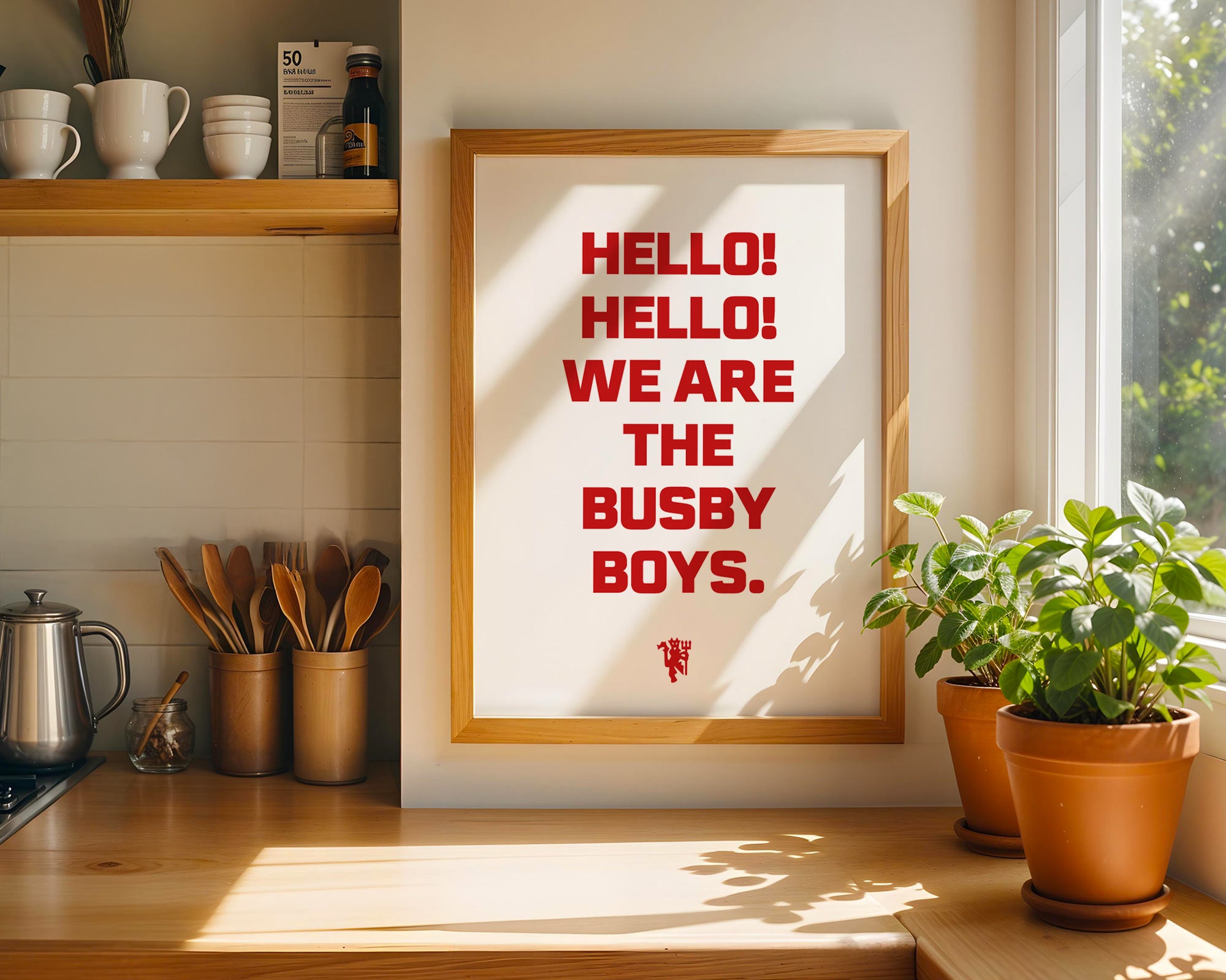 Framed poster with 'HELLO! HELLO! WE ARE THE BUSBY BOYS.' text in a kitchen setting.