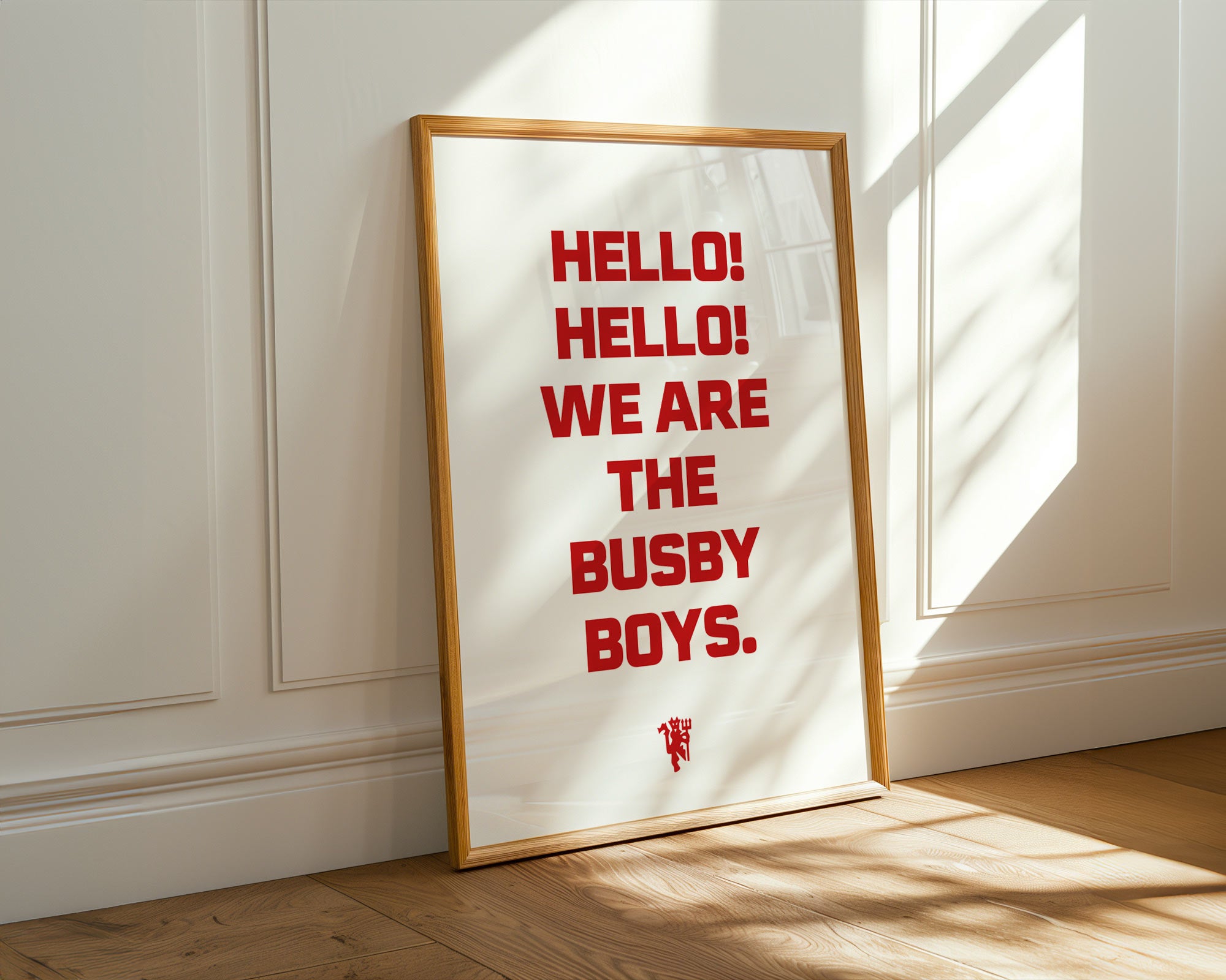 Framed poster with 'HELLO! HELLO! WE ARE THE BUSBY BOYS.' text on a white background, leaning against a wall.