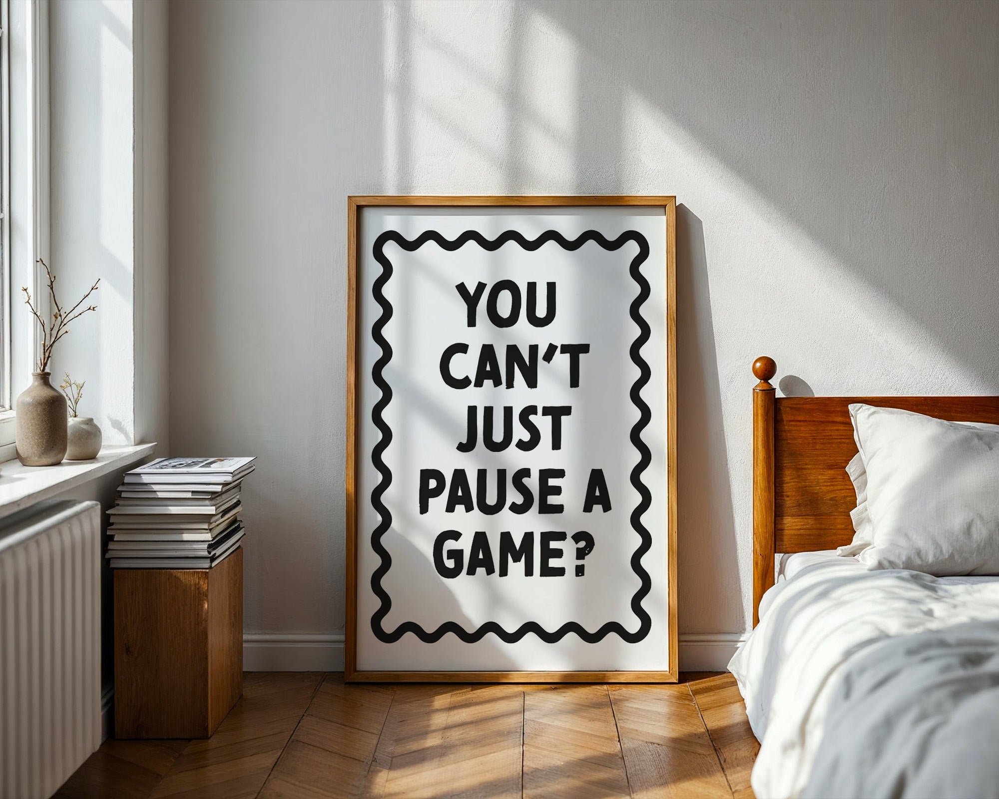 Framed poster with 'You can't just pause a game?' text in a bedroom setting.