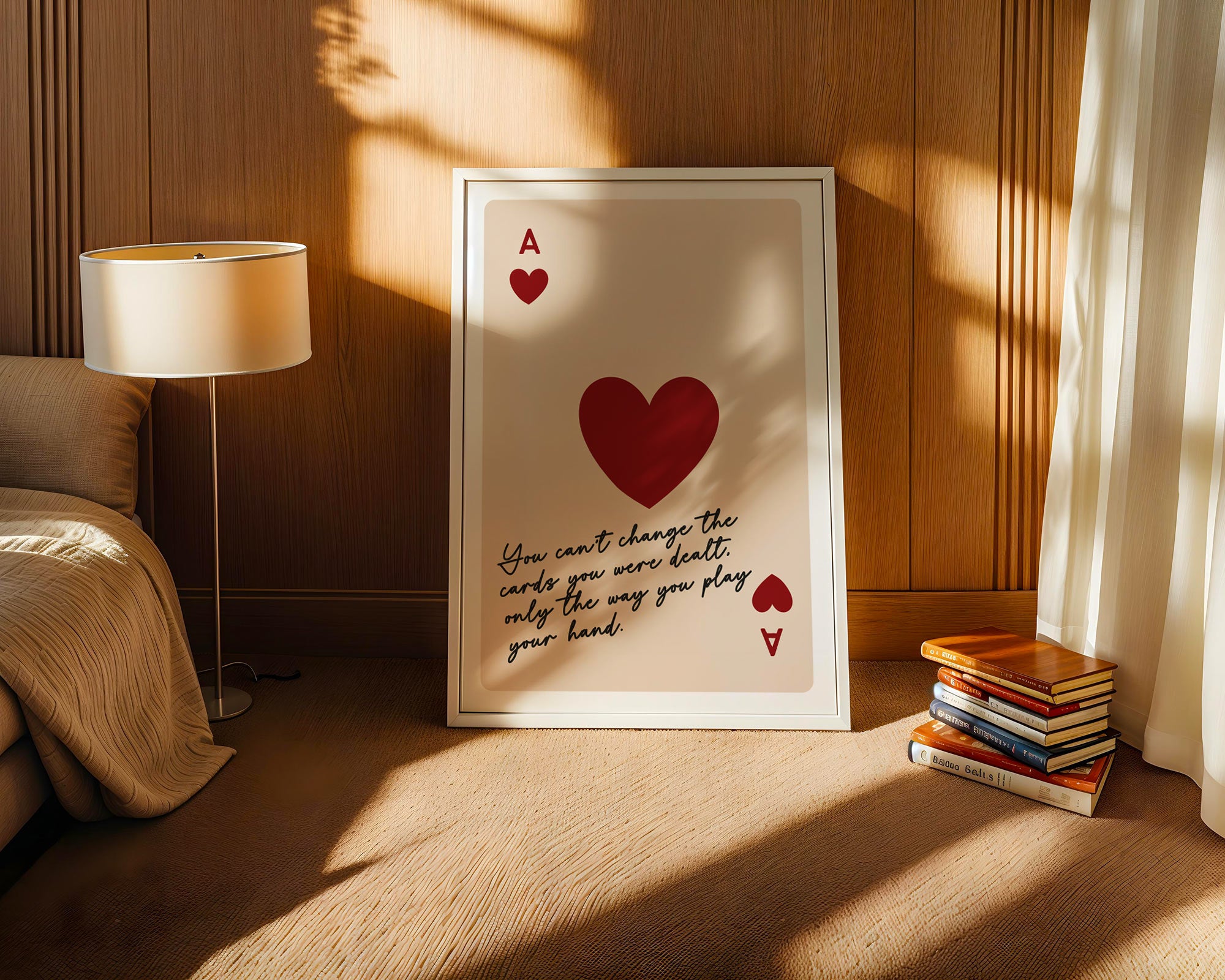 Framed artwork with a red heart and text in a cozy room with a lamp and books.