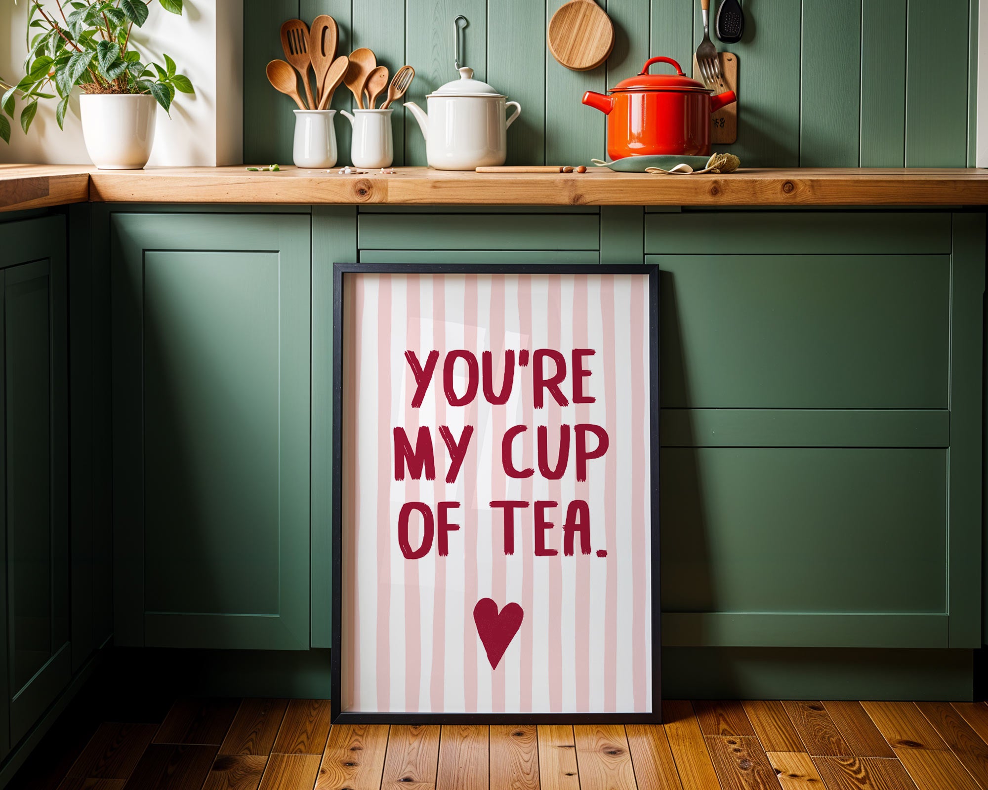Kitchen setting with a framed sign saying 'You're my cup of tea' on a wooden floor.