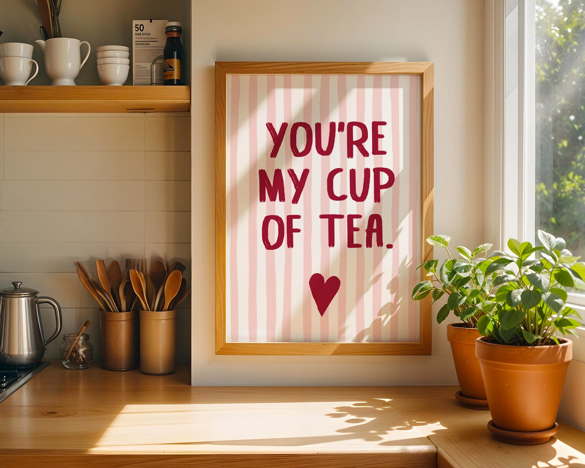 Framed print with 'You're my cup of tea' text in a kitchen setting with plants and cups.