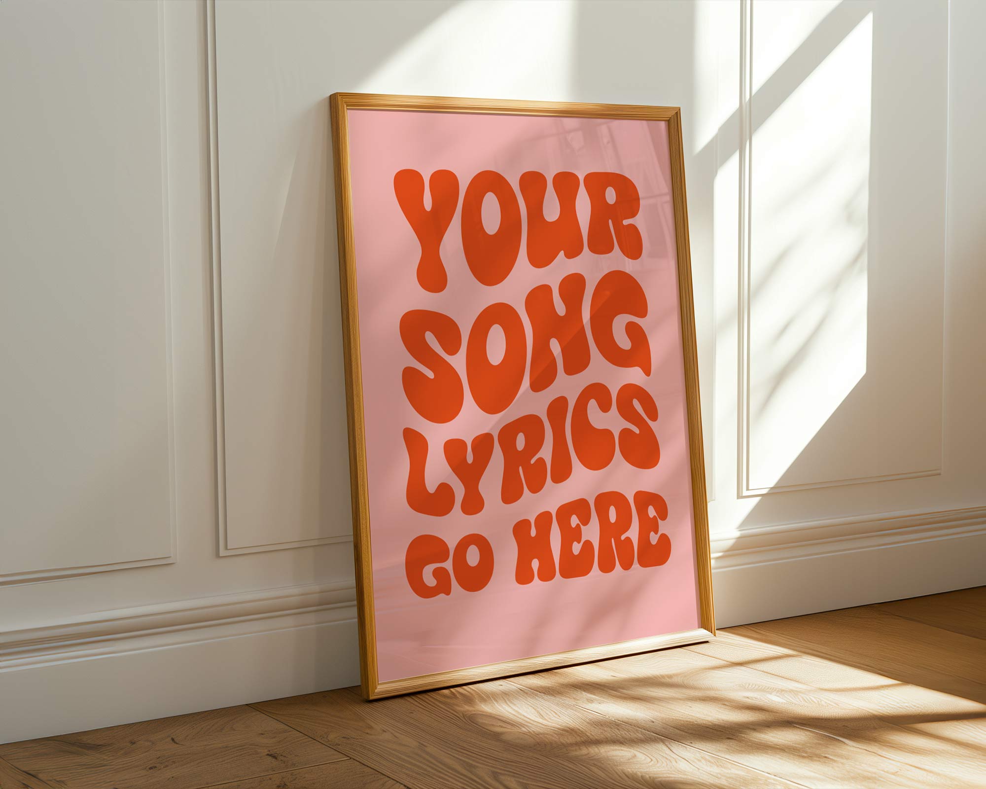 Framed poster with 'Your song lyrics go here' text on a pink background, leaning against a white wall.