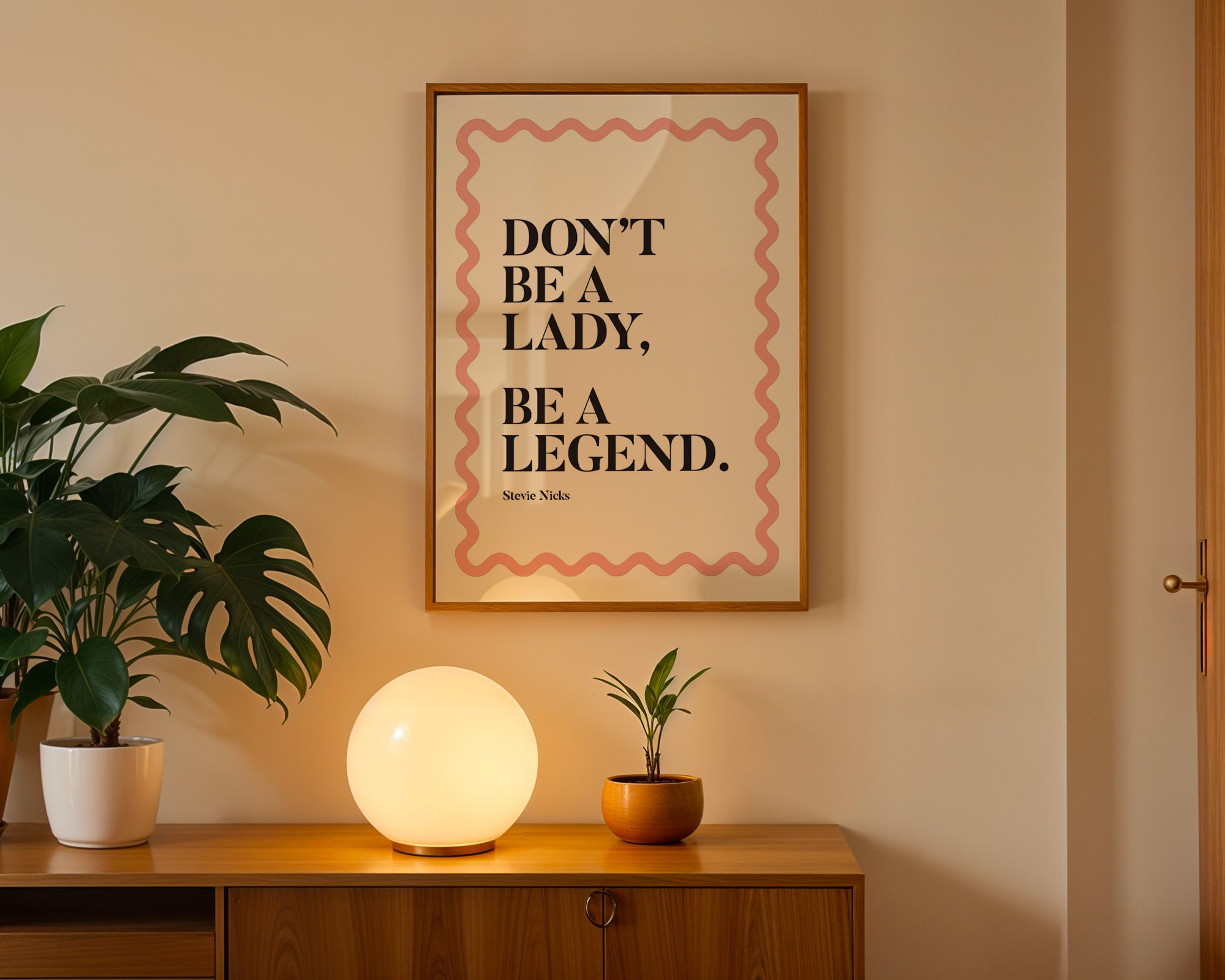 Framed quote 'Don't be a lady, be a legend' on a wall above a wooden cabinet with decorative items.