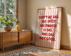 Room interior with a wooden sideboard, plant, and large framed poster with humorous text.