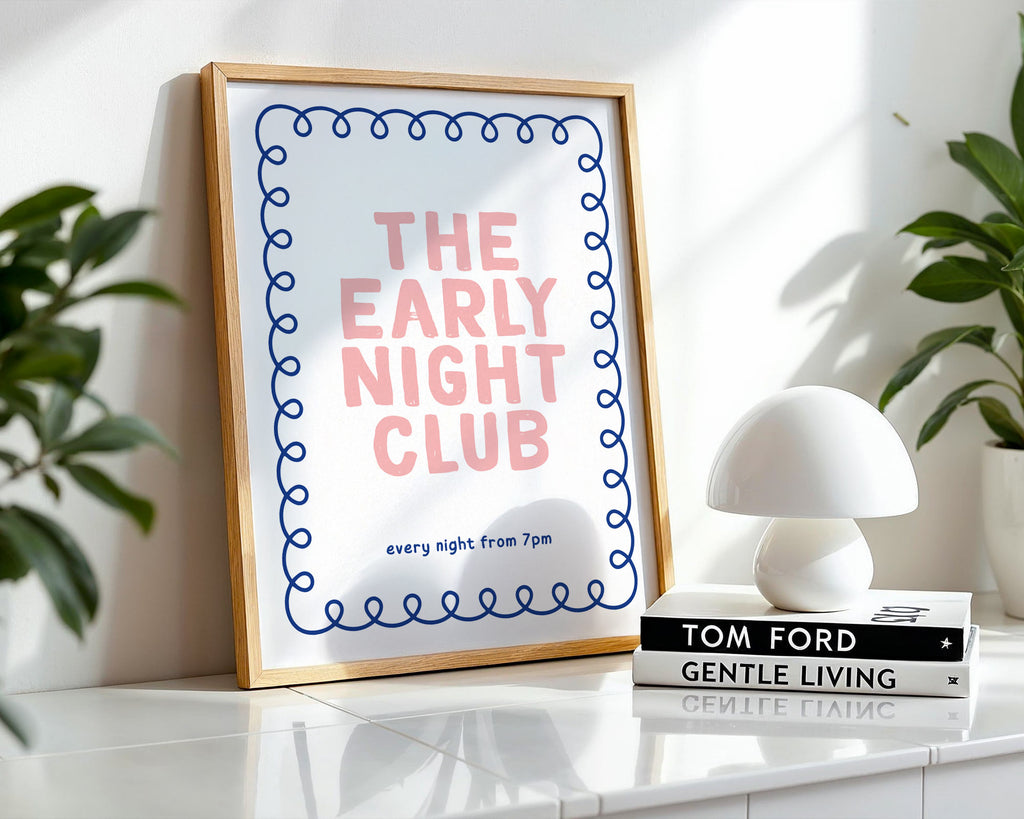 Framed print with 'The Early Night Club' text on a shelf with books and plants.