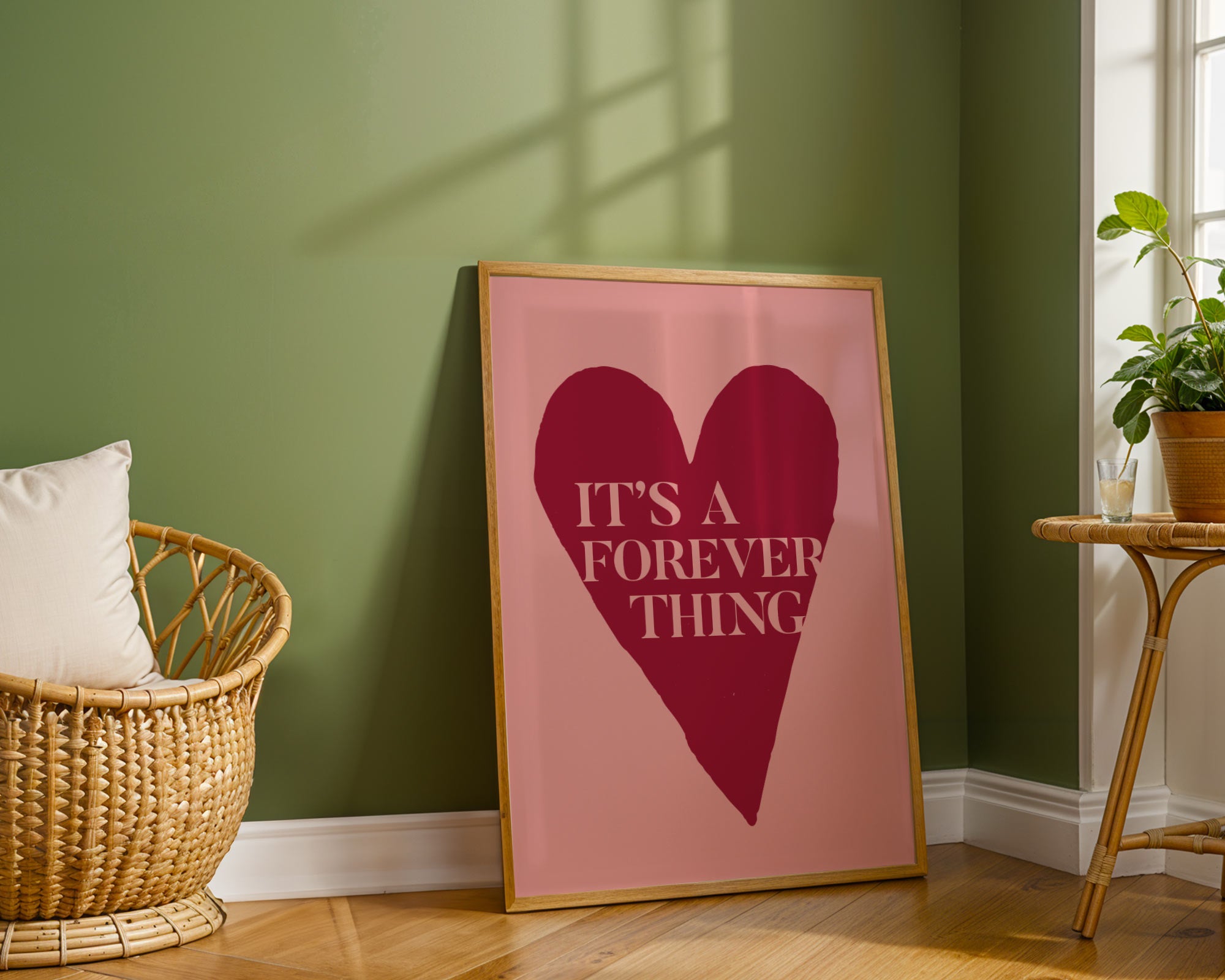 Framed artwork with a heart and text on a wall in a room with a basket and plant.