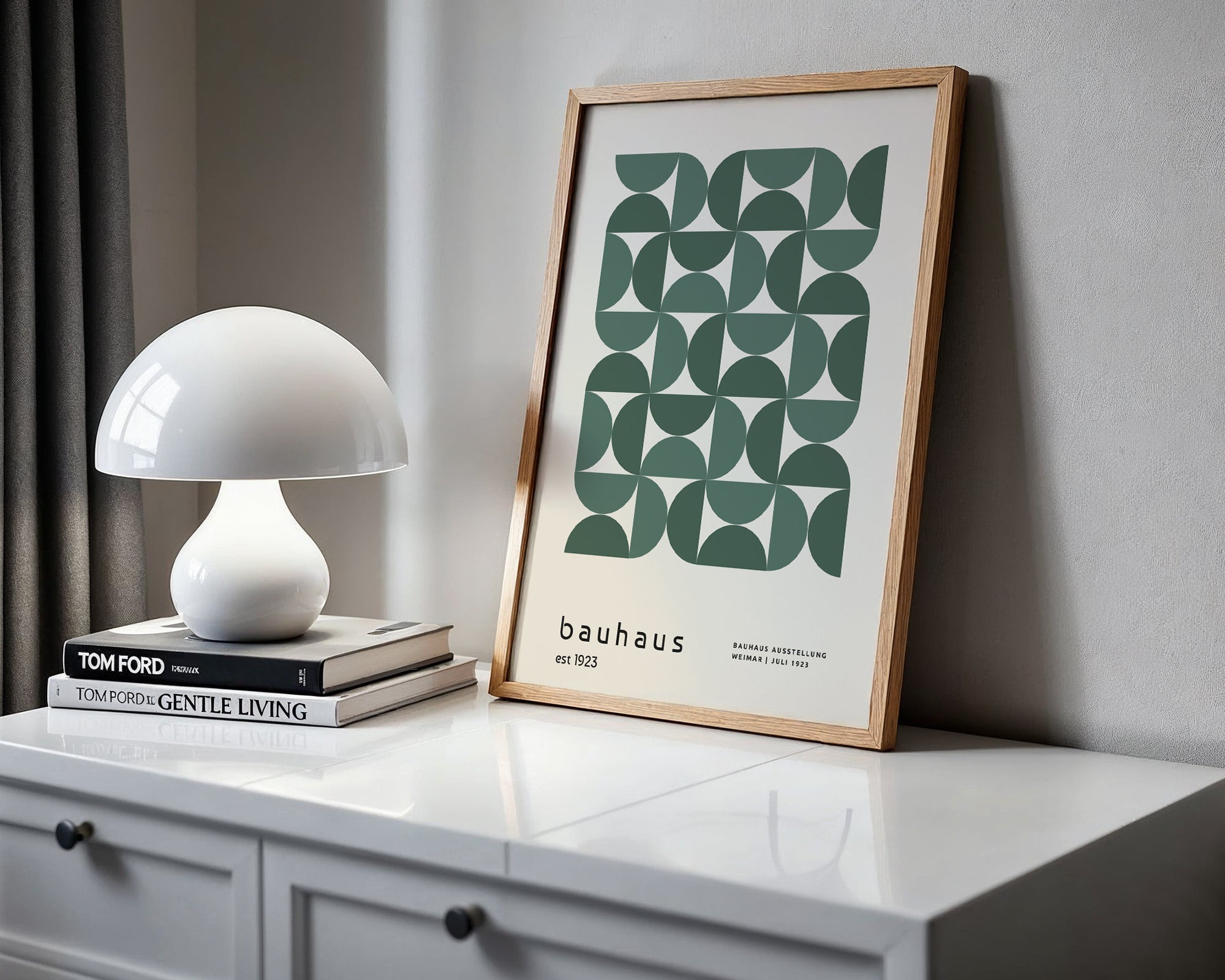 Framed Bauhaus poster on a white surface with a white lamp and books.