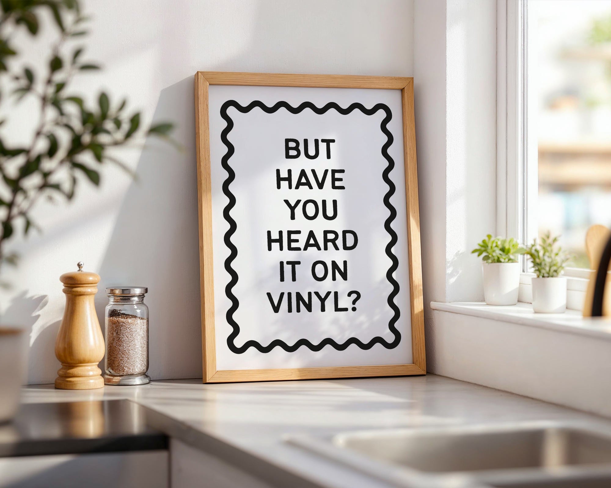 Framed poster with text 'BUT HAVE YOU HEARD IT ON VINYL?' on a kitchen counter.