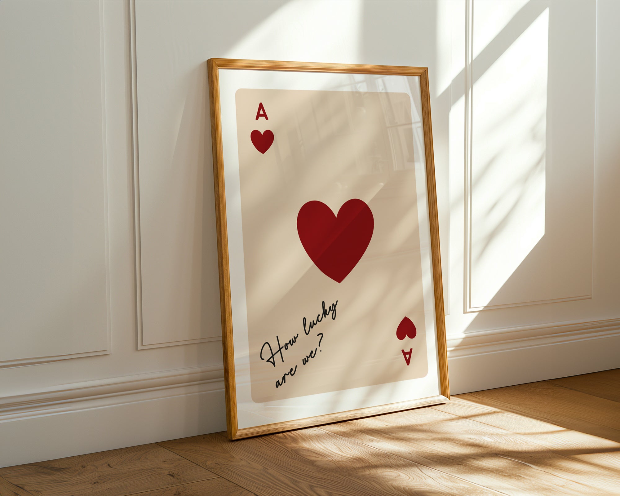 Framed artwork with a red heart and text on a beige background, leaning against a white wall.