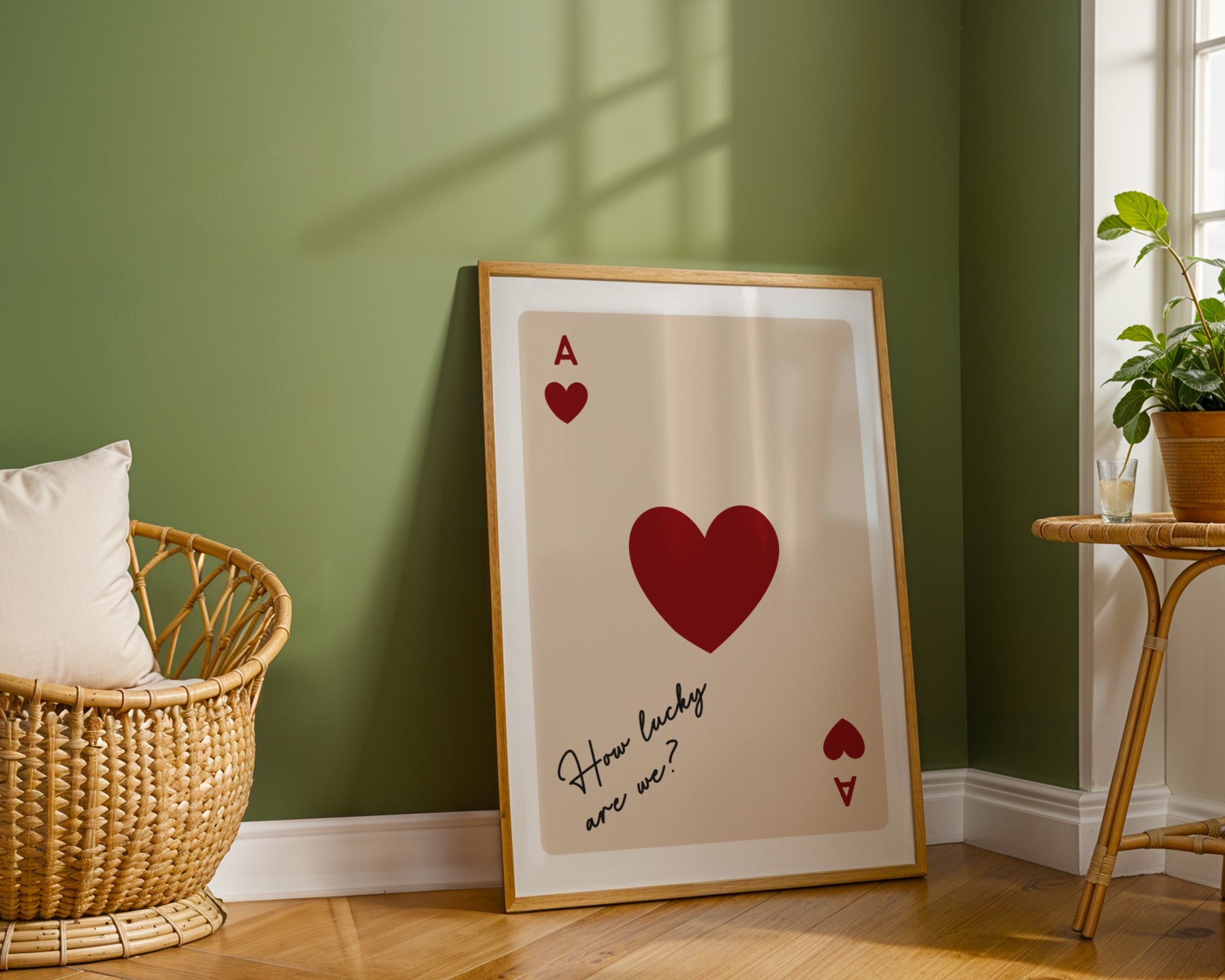 Framed artwork with a red heart and text on a wall in a room with a green wall, wicker basket, and small table.
