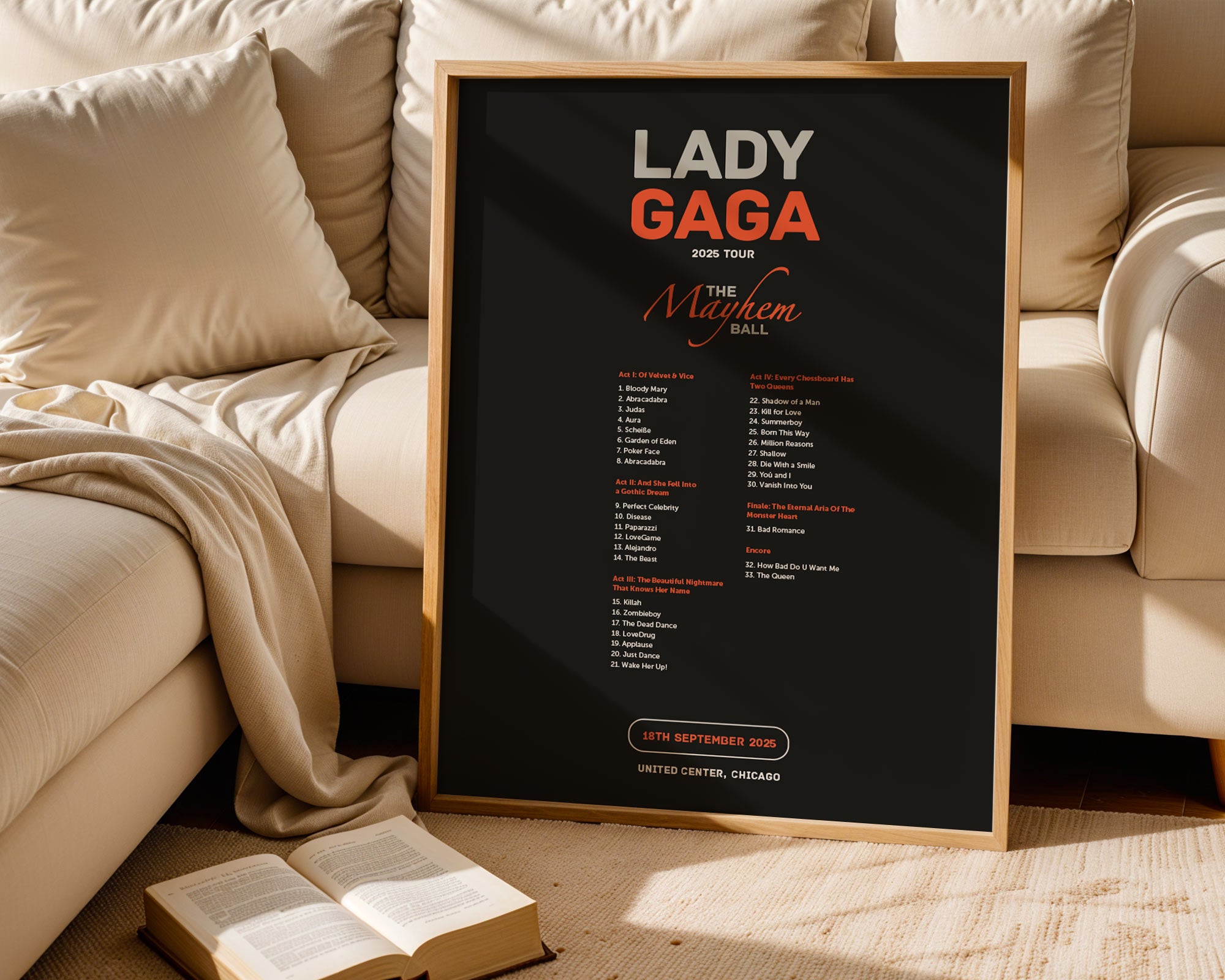 Framed poster of Lady Gaga's 'The Monster Ball' tour on a beige couch with an open book.