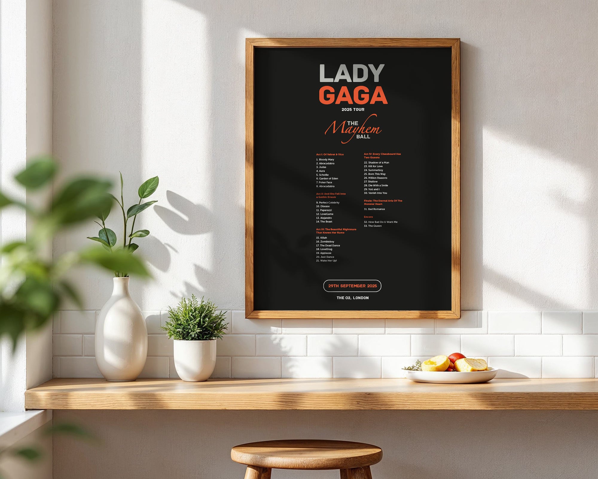 Framed poster of Lady Gaga on a wall above a wooden shelf with plants and fruit.