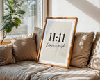 Framed artwork with '11:11 Make a wish' on a beige sofa with cushions.