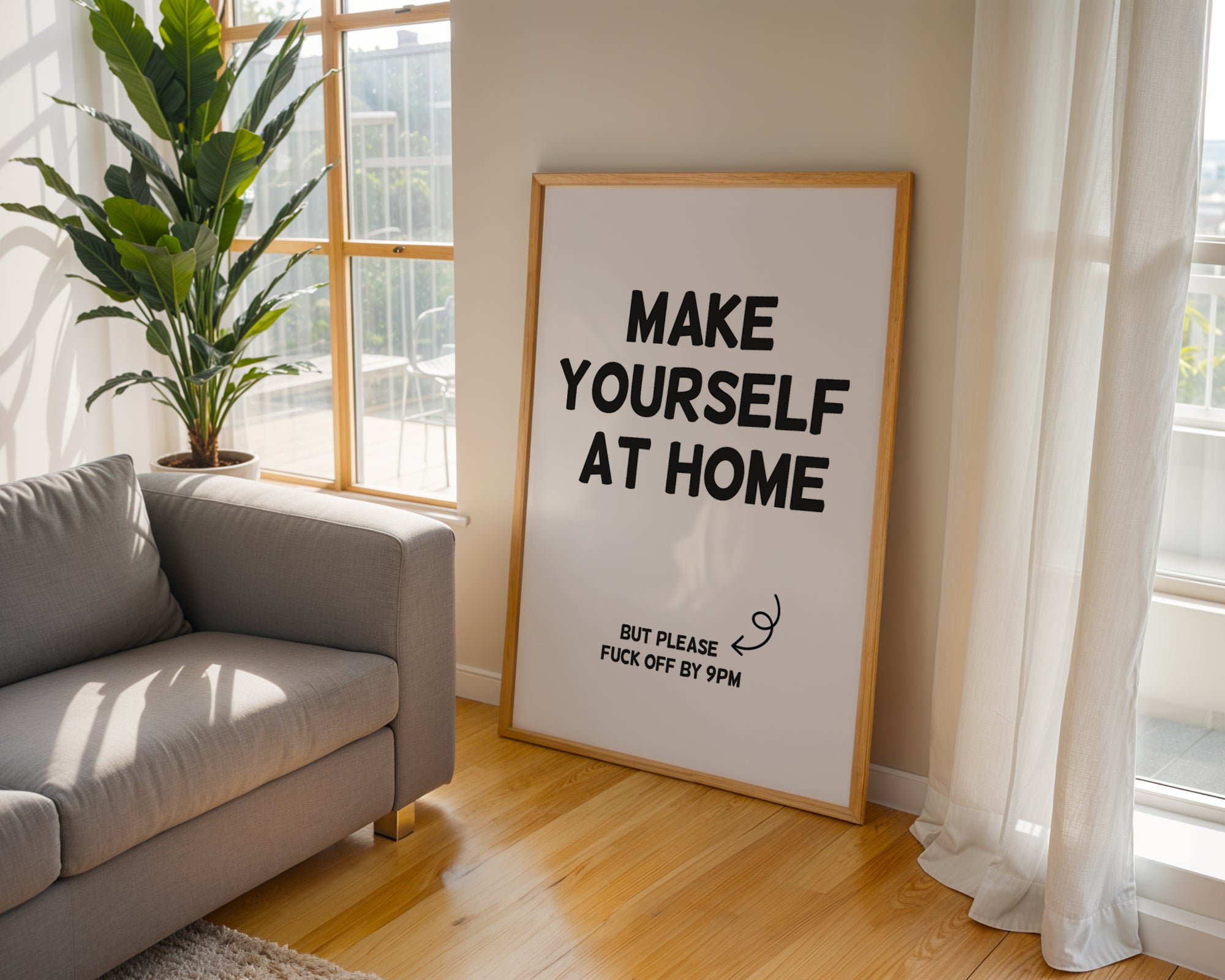 Sofa in a living room with a framed poster reading 'Make Yourself At Home, but please fuck off by 9pm'.