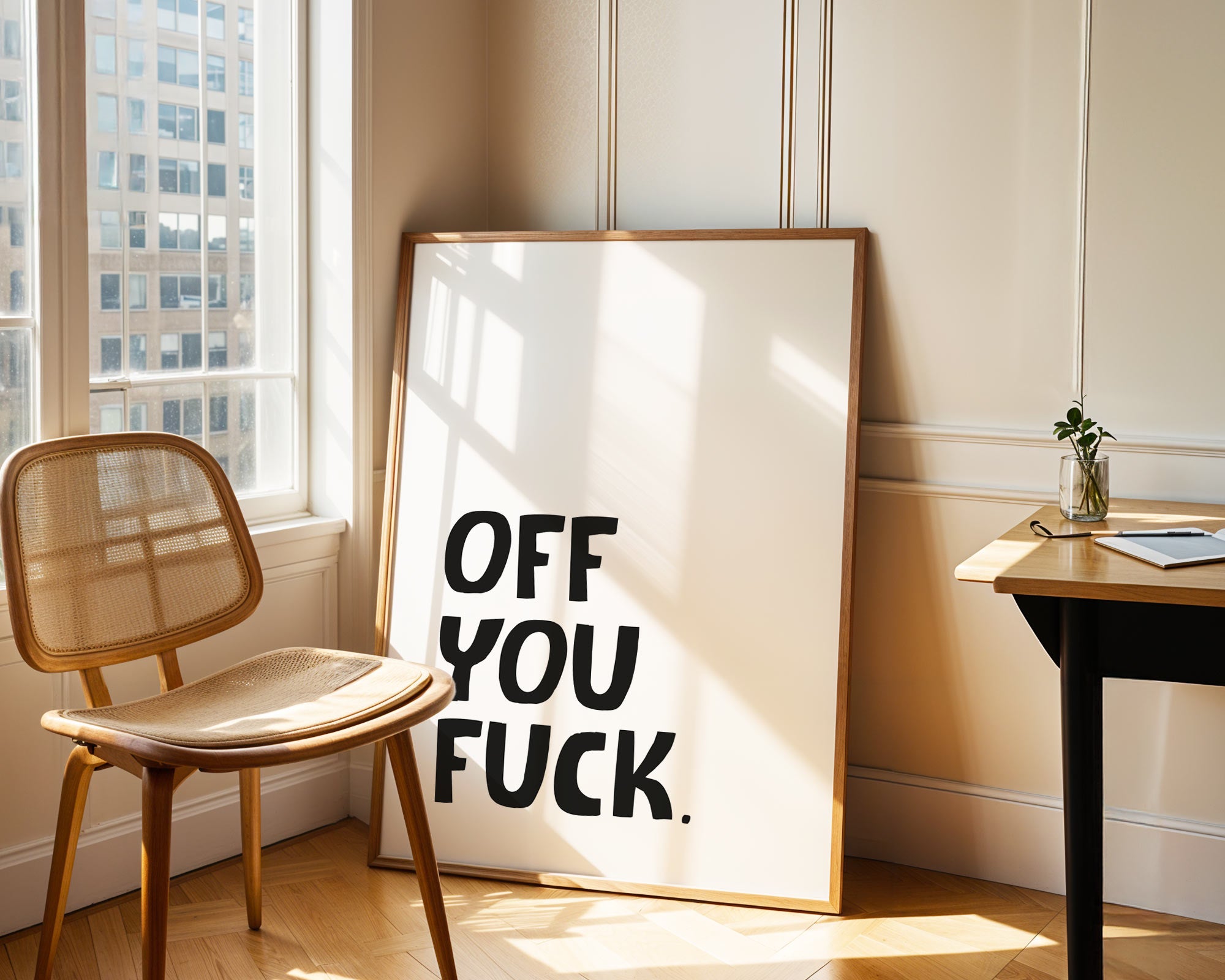 Framed artwork with text in a room with a chair and window.