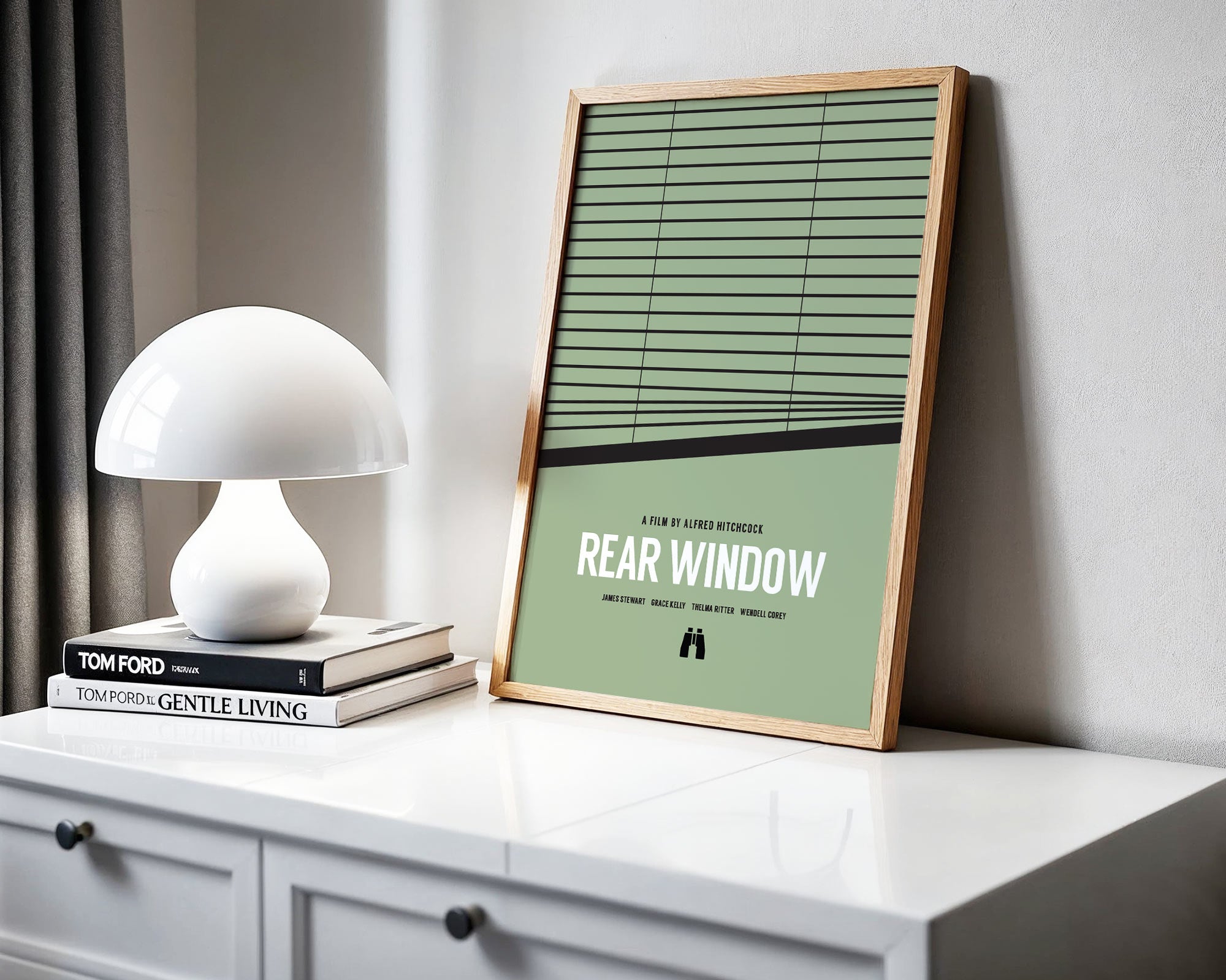 Framed poster of 'Rear Window' on a white surface with a lamp and books.