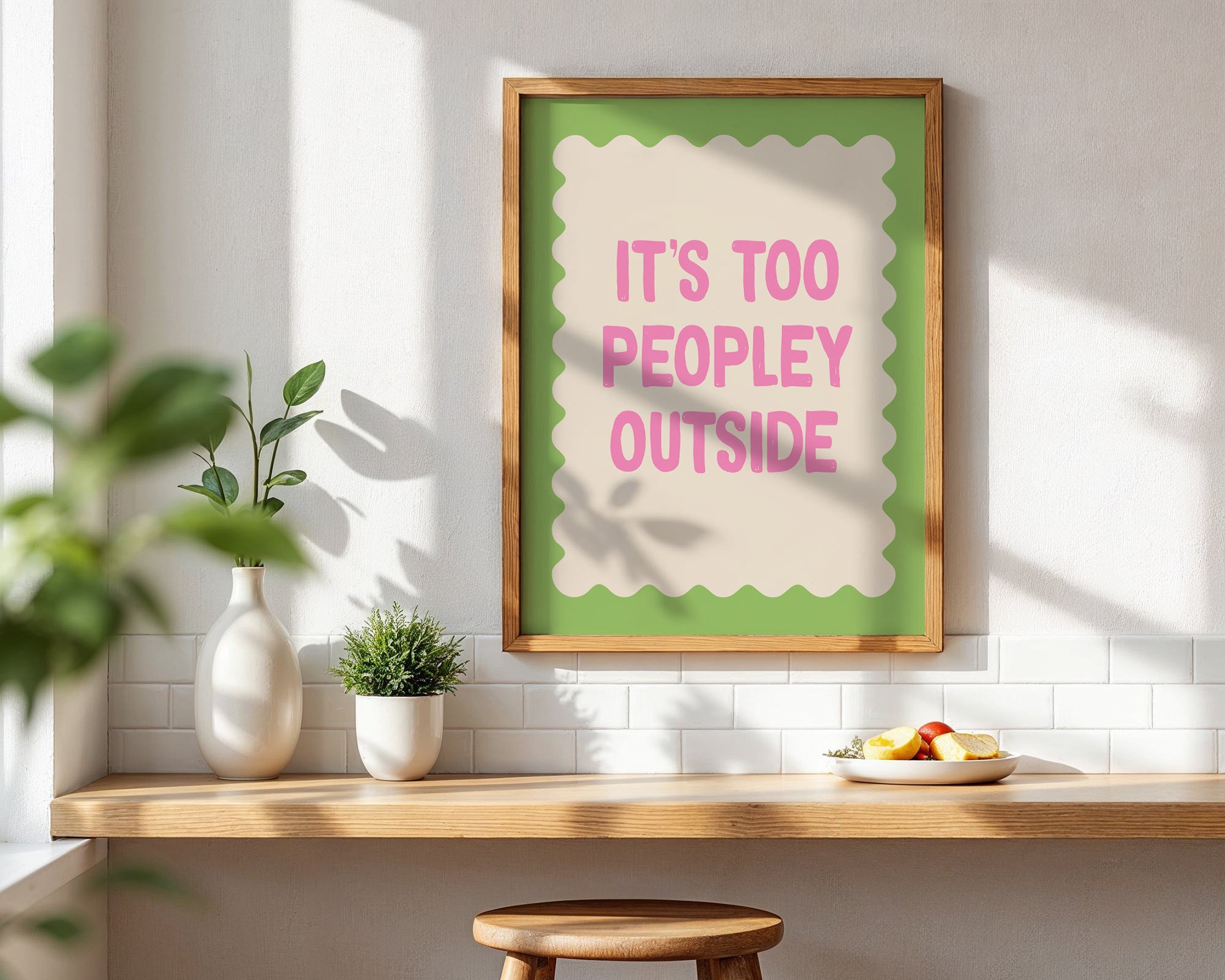 Framed poster with 'It's too peopley outside' text in a room with a table and plants.