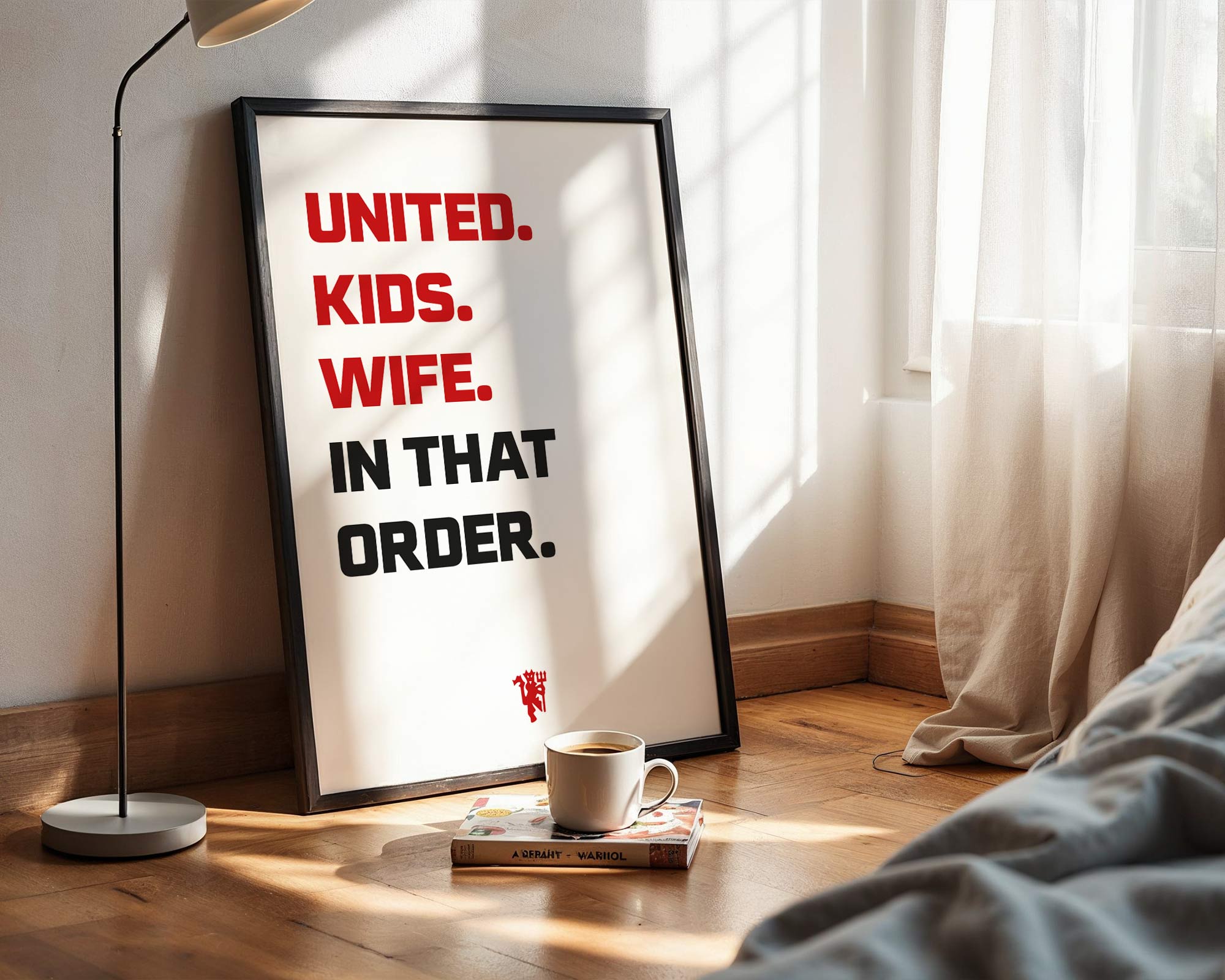 Framed poster with humorous text in a room with a lamp and book on a wooden floor.