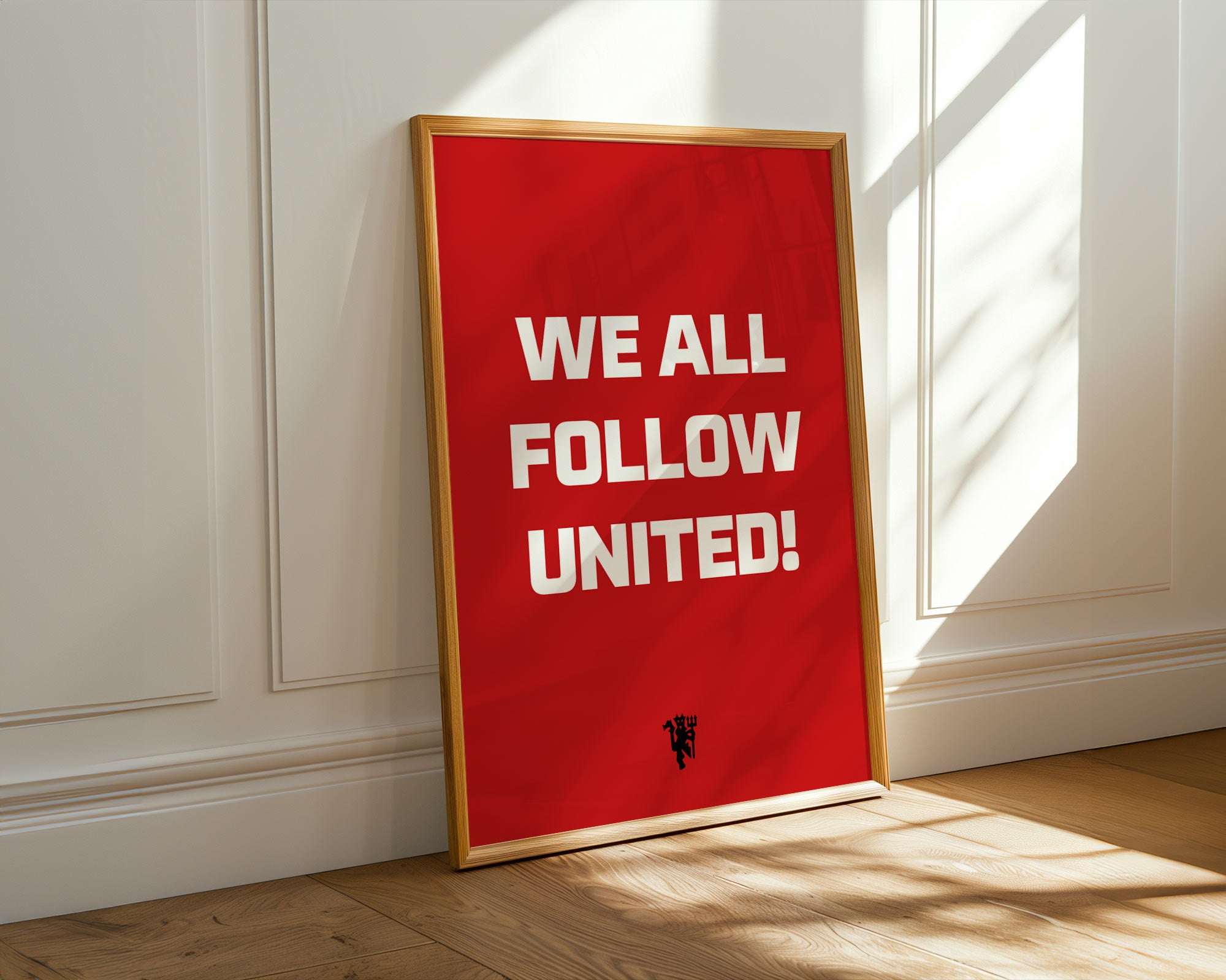 Red poster with 'WE ALL FOLLOW UNITED!' text in a gold frame on a white wall.