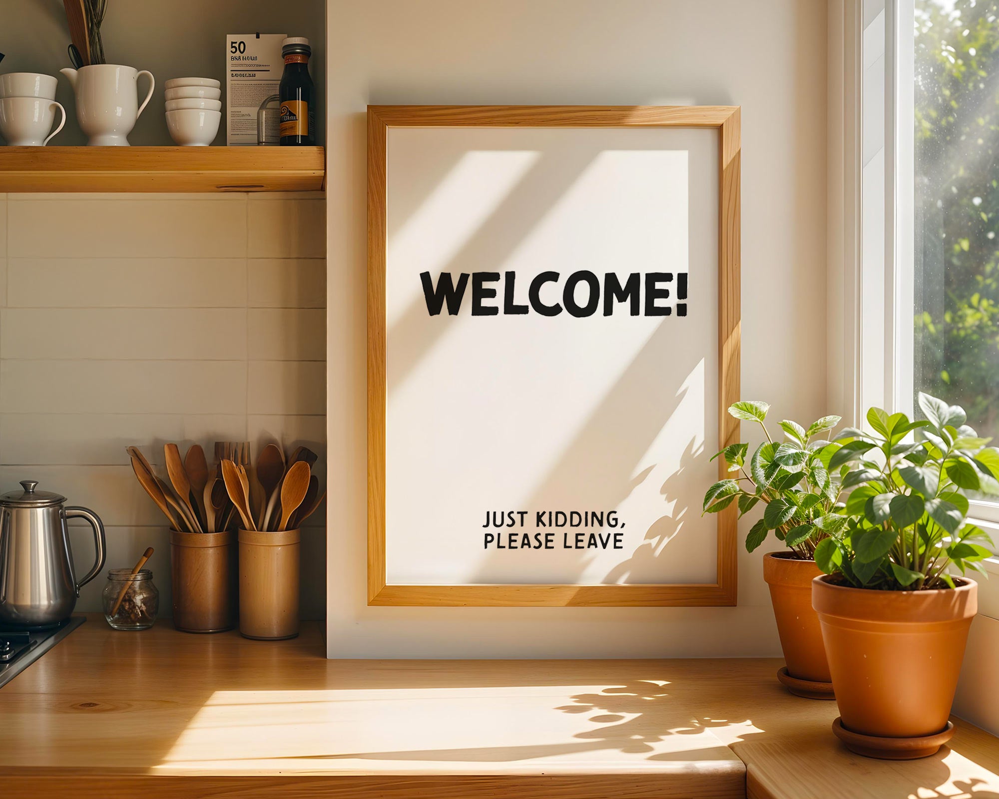 Framed sign with 'WELCOME! JUST KIDDING, PLEASE LEAVE' text in a kitchen setting.
